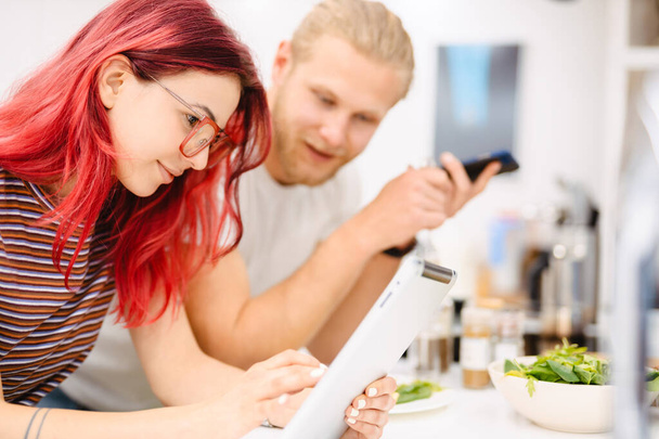 Young white couple using gadgets while having lunch in kitchen at home - Fotografie, Obrázek