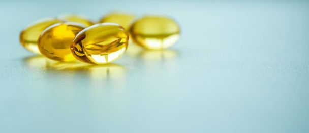 Fish oil capsules on a blue background with copy space. - Photo, Image