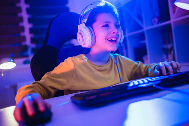 Мальчик играет в видеоигры в темной комнате - Фото, изображение