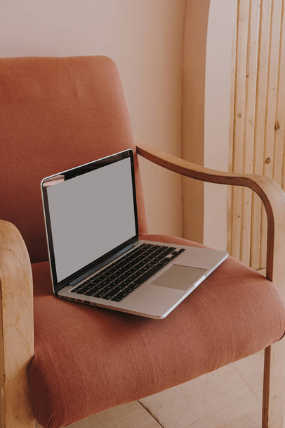 Бланк экрана ноутбука на удобном персиковом кресле. Дизайн интерьера дома. Копировать макет космоса. Шаблон бизнес бренда - Фото, изображение