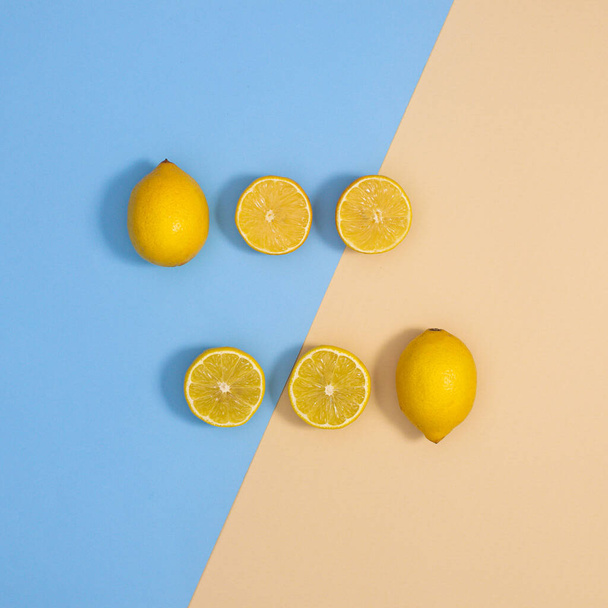 Cretive layout with whole and sliced organic lemon on pastel blue and beige background. Flat lay minimal cistrus food composition - Foto, Imagem