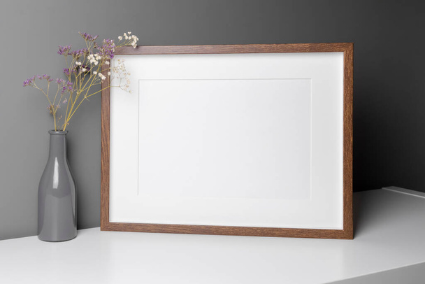 Landscape wooden frame mockup for artwork, photo and print presentation with dry flowers interior decorations over grey wall. - Foto, afbeelding