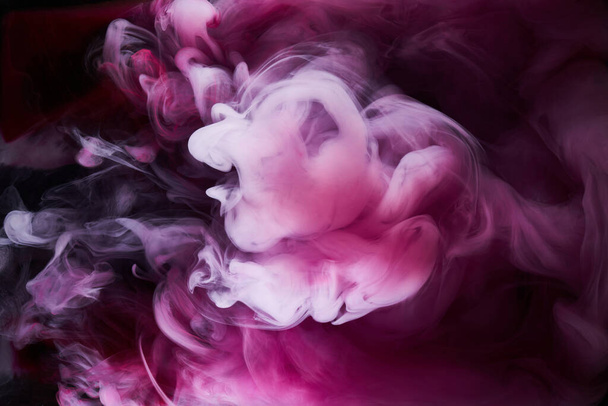 Roze rook op zwarte inkt achtergrond, kleurrijke mist, abstracte wervelende aanraking oceaan zee, acrylverf pigment onderwater - Foto, afbeelding