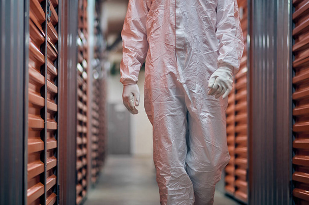 Worker in a hazmat suit inspecting in the storage equipment - Photo, image