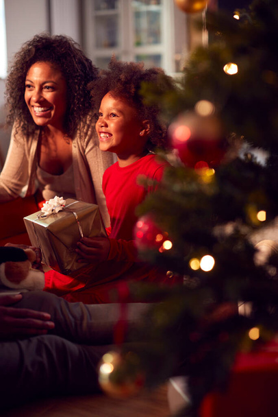 Family Exchanging And Opening Gifts Around Christmas Tree At Home - Foto, imagen