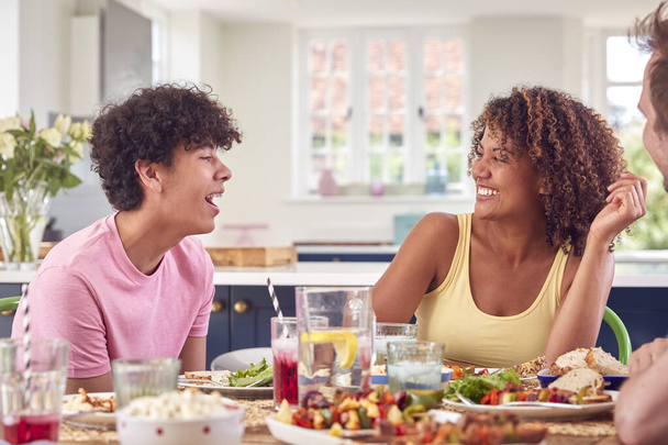 Family With Teenage Son Sitting Around Table At Home Eating Meal Together - Photo, Image