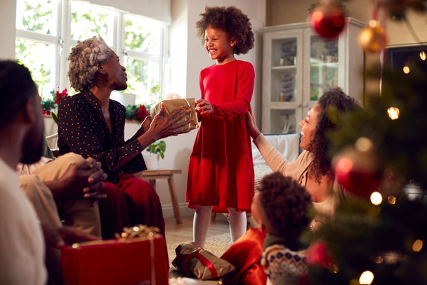 Multi-generatie familie uitwisselen en openen geschenken rond de kerstboom Thuis - Foto, afbeelding