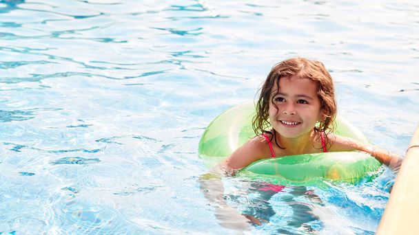 Young Girl Learning To Swim With Inflatable Ring In Swimming Pool On Summer Vacation - Zdjęcie, obraz