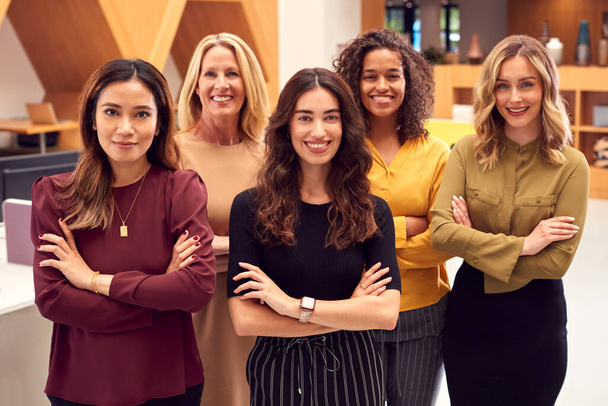Portret van een multicultureel vrouwelijk businessteam staand in een modern open kantoorgebouw - Foto, afbeelding