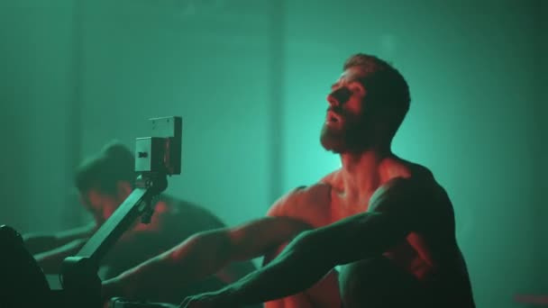 Slow motion: Man and woman training on a rowing machine in gym - Footage, Video