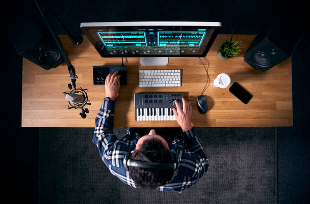 Felülnézetből férfi zenész a munkaállomáson billentyűzet és mikrofon a stúdióban - Fotó, kép