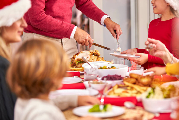 Grandfather Carving Turkey As Multi-Generation Family Sit Down To Eat Christmas Meal Together - Foto, immagini