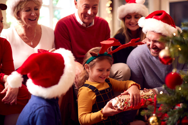 Mehrgenerationenfamilie tauscht Geschenke rund um den Weihnachtsbaum zu Hause aus - Foto, Bild