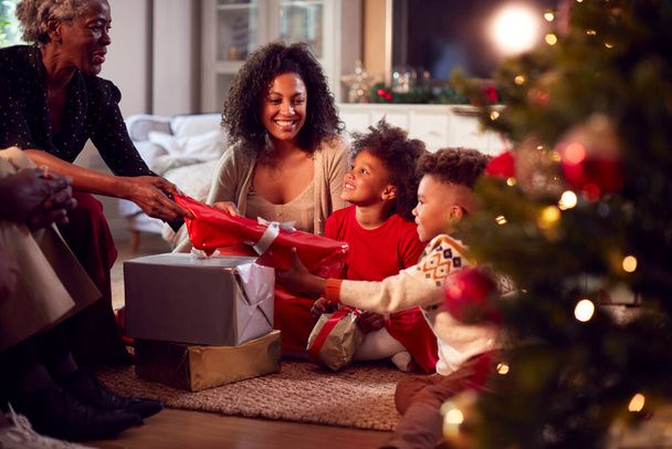 Multi-Generation Family Exchanging And Opening Gifts Around Christmas Tree At Home - Valokuva, kuva