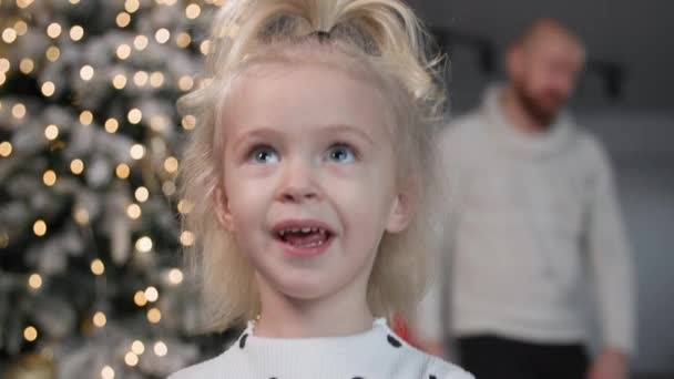 portrait de charmante fille douce souriant et regardant autour de l'arrière-plan de l'arbre du Nouvel An dans la chambre - Séquence, vidéo
