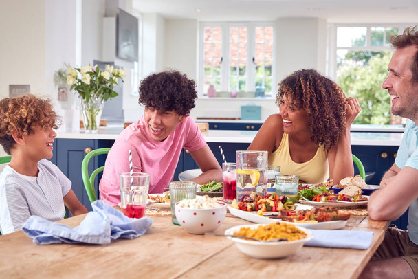 Family Sitting Around Table At Home Eating Meal Together - Photo, image