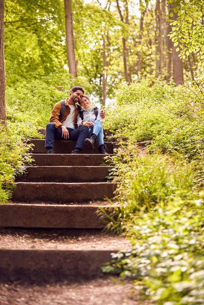 Hiking Couple With Backpacks Sitting On Steps On Path Through Trees In Countryside Together - Fotoğraf, Görsel