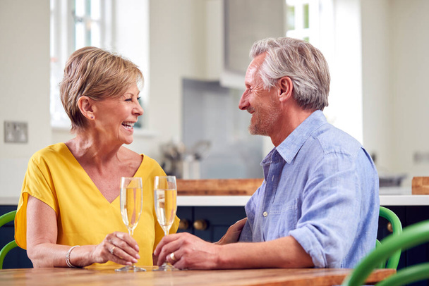 Retired Couple Celebrating With Glass Of Champagne At Home On Date Night Together - Foto, afbeelding