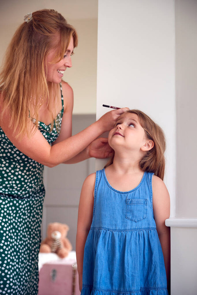 Mother Measuring Daughter's Height And Marking On Wall At Home - Φωτογραφία, εικόνα