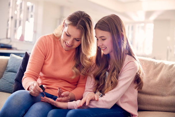 Mother And Daughter Having Fun Sitting On Sofa At Home Doing Nails Together - Zdjęcie, obraz