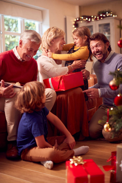 Usean sukupolven perheen vaihtaminen ja avaaminen lahjoja ympäri joulukuusi kotona - Valokuva, kuva