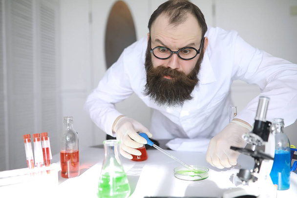 Químico maluco. Um cientista louco realiza experimentos em laboratório científico. Realiza pesquisas usando um microscópio. - Foto, Imagem