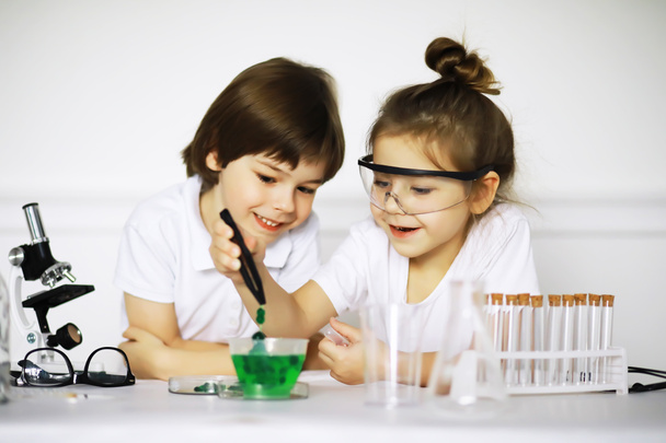 Two cute children at chemistry lesson making experiments isolated on white backgroun - Photo, Image