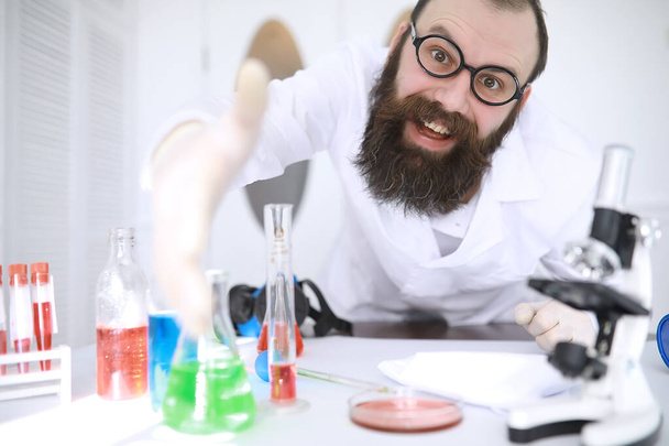 Χημικός τρελός. Ένας τρελός επιστήμονας διεξάγει πειράματα σε επιστημονικό εργαστήριο. Διεξάγει έρευνα χρησιμοποιώντας μικροσκόπιο. - Φωτογραφία, εικόνα