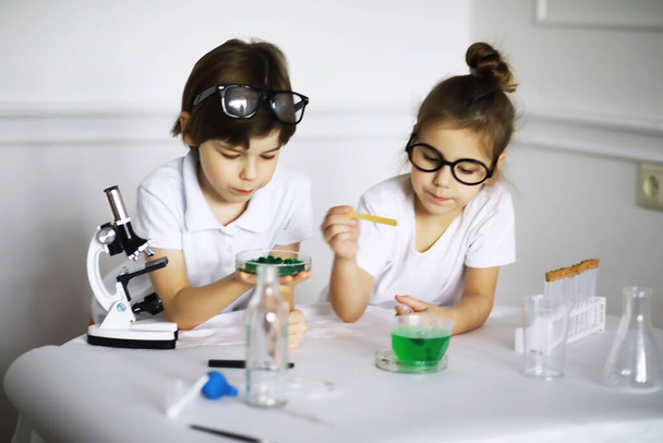 Két aranyos gyerek kémiaórán kísérleteket csinál elszigetelt fehér backgroun - Fotó, kép