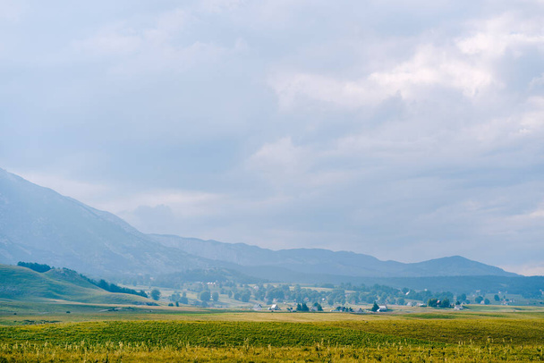 Durmitor Milli Parkı 'nda yeşil vadi, dağlar ve bulutlu gökyüzü karşısında. - Fotoğraf, Görsel