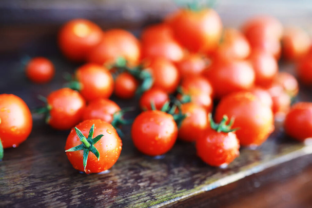 Ekologiczne świeże pomidory wiśniowe na drewnianym tle. - Zdjęcie, obraz