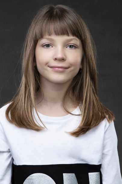 A beautiful ten year old girl is looking at the camera and smiling. - Fotó, kép