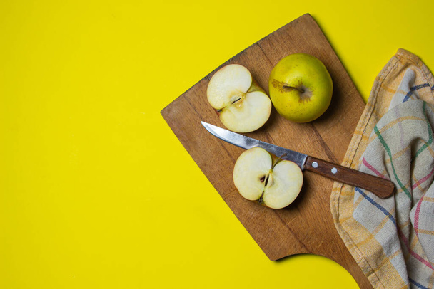 黄色の背景にりんご。木の板の上のリンゴの半分. - 写真・画像