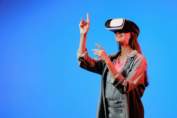 Brýle virtuální reality VR na dívce. Dívá se do budoucnosti. Dotýkám se nového. Fantastický virtuální svět. Pocit ponoření, překvapení, rozhořčení, strachu, strachu, smíchu, radosti. Koncept NFT. - Fotografie, Obrázek