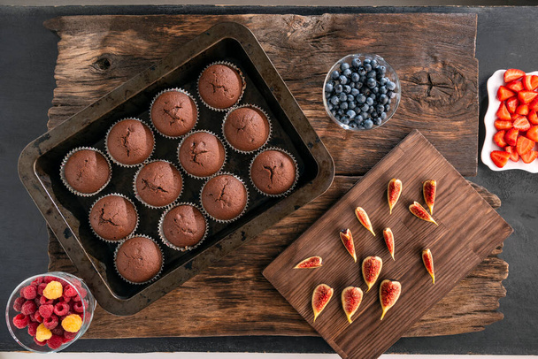 Solo magdalenas de chocolate al horno en Bakeware y frutas y bayas de temporada. Acostado. Vista superior - Foto, Imagen