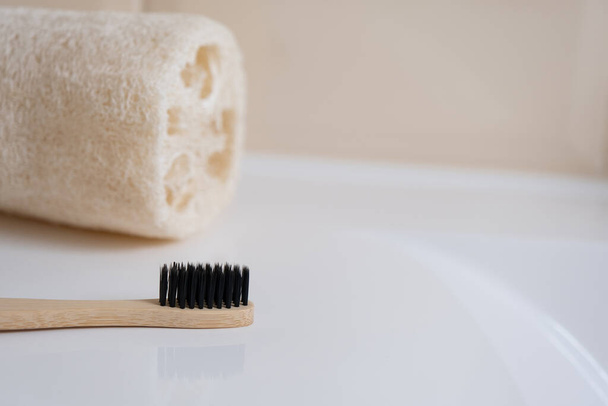 Spazzolino da denti in bambù e spugna naturale con setole nere sul lavabo in bagno. Beauty, spa e wellness concept, spazio fotocopiato - Foto, immagini