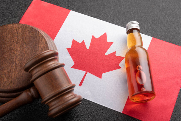 Koncepcja alkoholu i przestępstw. Butelka alkoholu i drewniany młotek jako symbol prawa i bandery Kanady. - Zdjęcie, obraz