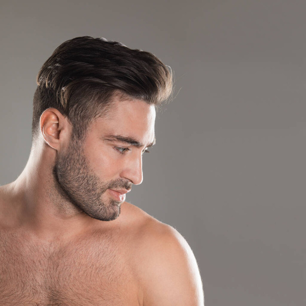 Portrait of handsome young naked man with stylish haircut and bristle over gray background - Foto, immagini