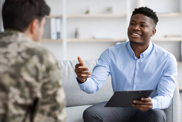 Friendly african american psychologist having conversation with soldier - 写真・画像