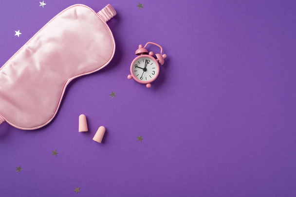 Top view photo of the big silk eye mask and cute pink clock with two earplugs with scattered confetti in shape of stars on the purple isolated background copyspace - Fotoğraf, Görsel