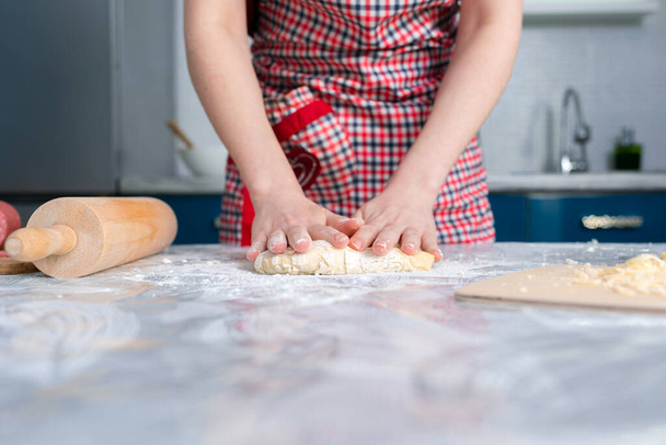 The woman in the apron knead the dough. Close - up view of hands. Copy space. The concept of a homemade food. - Foto, immagini