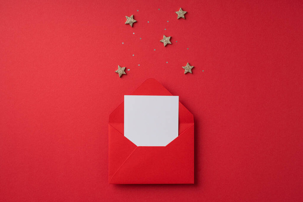 Top view photo of valentine's day decorations open red envelope with paper sheet stars and sequins on isolated red background with copyspace - Photo, Image