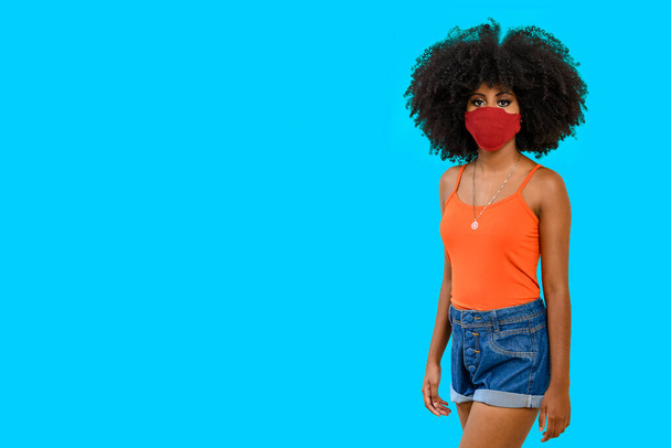portrait d'une adolescente noire avec une coiffure afro, avec écran facial, vêtue de vêtements décontractés, isolée sur fond gris. - Photo, image