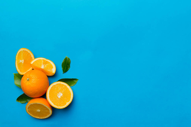 新鮮なフルーツオレンジのスライスを着色された背景に。最上階だ。コピースペース。創造的な夏のコンセプト。コピースペースと最小限のフラットレイアウトで柑橘類の半分. - 写真・画像