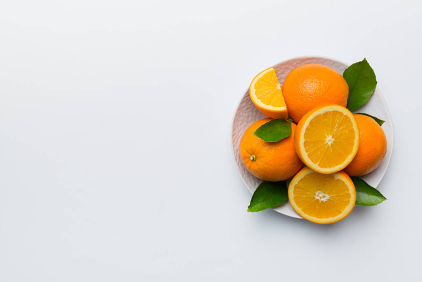 Puesta plana de fruta fresca de naranja con rebanadas en plato sobre fondo de color. Vista superior con espacio de copia. - Foto, Imagen