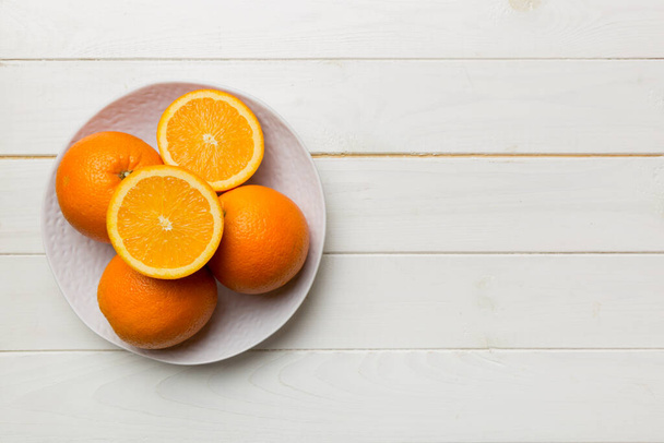 Flache Lage von frischen Orangenfrüchten mit in Scheiben geschnittenen Teller auf farbigem Hintergrund. Draufsicht mit Kopierraum. - Foto, Bild