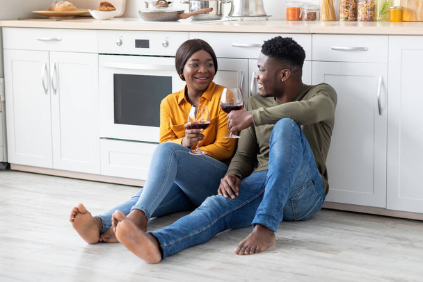 Happy Black Couple Relaxing In Kitchen Together, Drinking Red Wine And Chatting - Photo, Image