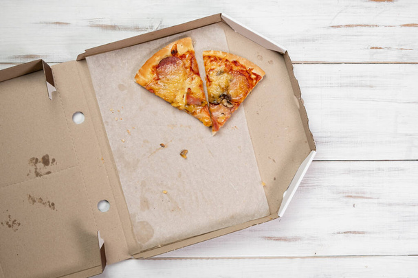 Pizza pieces in a cardboard box. white wood background. Food concept. View from above. - Foto, afbeelding