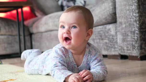 Sonriente bebé acostado en un estómago y aprendiendo a gatear - Metraje, vídeo