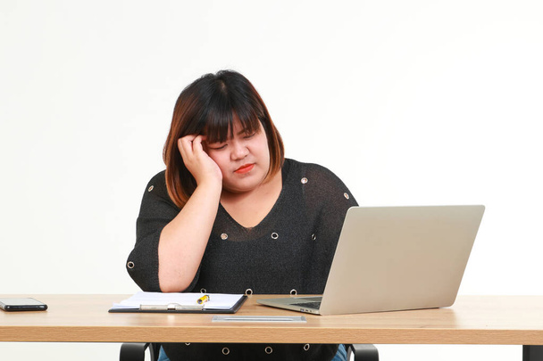 A kövér ázsiai nő sokáig ül a munkahelyén laptoppal. Fáradtnak és stresszesnek érezte magát. Az elhízott emberek egészségügyi ellátásának fogalma. egészségügyi problémák. Fehér háttér. - Fotó, kép